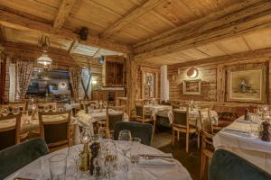 un restaurante con mesas y sillas blancas y techos de madera en Le Vieux Chalet, en La Clusaz