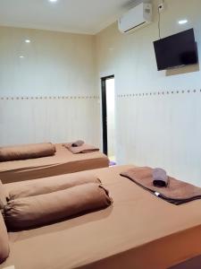 Cette chambre dispose de 2 lits et d'une télévision murale. dans l'établissement De Patuk Homestay, à Yogyakarta