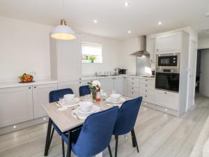 uma cozinha com uma mesa de jantar e cadeiras azuis em Harry's Lodge em Chesterfield
