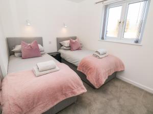 um quarto com duas camas com lençóis cor-de-rosa e uma janela em Harry's Lodge em Chesterfield