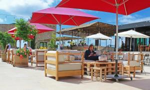 a woman sitting at a table under a red umbrella at Bkerzay in Baakleen