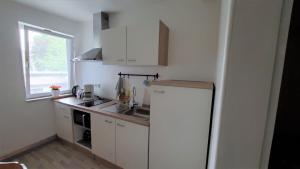a small kitchen with a refrigerator and a window at Landgasthof Steuber - Hotel garni in Bromskirchen