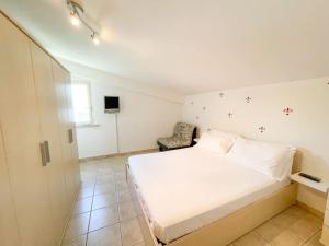 1 dormitorio con 1 cama blanca y 1 silla en Homiday - Tamerici Attico, en Pineto