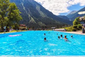 a group of people swimming in a swimming pool in the mountains at Appartements Fürstalm Alpendorf in Gerlos