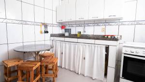 a kitchen with white cabinets and a table and stools at Apto a 300 metro da praia - WIFI 200MB - TV Smart - Cozinha equipada - Ar condicionado in Rio das Ostras
