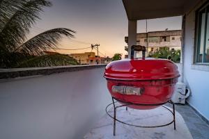 リオ・ダス・オストラスにあるApto a 300 metro da praia - WIFI 200MB - TV Smart - Cozinha equipada - Ar condicionadoの建物横に座る赤い容器