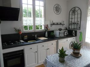 a kitchen with white cabinets and a sink and a microwave at MAISON Classée 3* in Gujan-Mestras