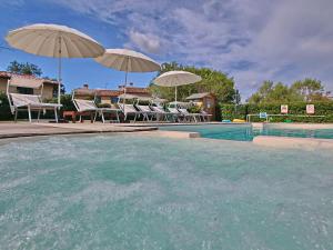 una piscina con 2 sombrillas y sillas y una piscina en Cottage in Montelabbate with Pool Garden BBQ Parking, en Montelabbate