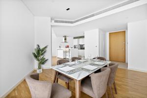 a white dining room with a table and chairs at VayK - Spacious One Bedroom with Ain Views in Dubai