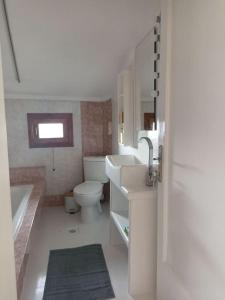 een badkamer met een toilet, een wastafel en een bad bij Cozy house in Tagarades