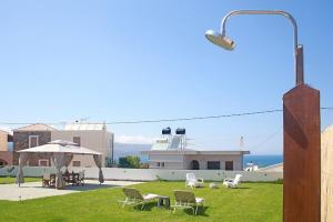 a view of a house with chairs and an umbrella at Pilot's Cottage Villa With Sea View in Tavronitis