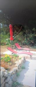 a red chaise lounge and a chair in a yard at L'Oustaou Dorey in Saint-Cyr-sur-Mer