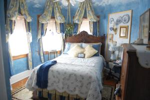 a bedroom with a bed with blue walls and windows at Schuster Mansion Bed & Breakfast in Milwaukee