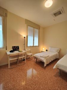 een slaapkamer met 2 bedden, een tafel en een bureau bij Casa dello Studente in Vittorio Veneto