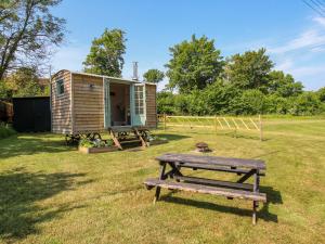 a wooden cabin with a picnic table in the grass at Acres Meadow in Dorchester