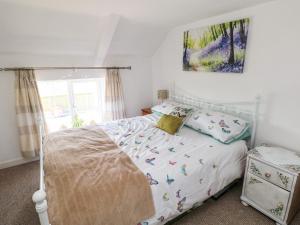 Un dormitorio con una cama con una colcha blanca con pájaros. en Daisys Cottage, en Burry Port
