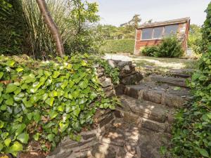 un jardín con una pared de piedra y una casa en Daisys Cottage, en Burry Port