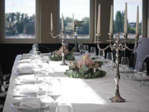 Hotel Fährhaus km734 في دوسلدورف: طاولة طويلة مع الأطباق البيضاء وكؤوس النبيذ