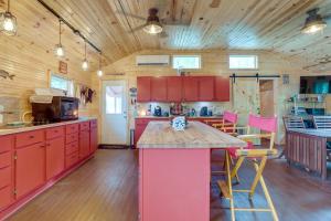 een grote keuken met rode kasten en roze aanrechtbladen bij Rock River Hideaway on Private 5-Acre Island! in Oregon