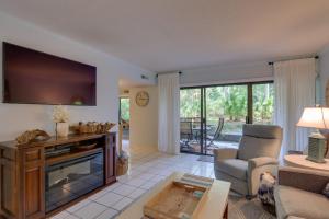 ein Wohnzimmer mit einem TV, einem Sofa und einem Stuhl in der Unterkunft Serene Hilton Head Island Condo with Community Pool! in Hilton Head Island