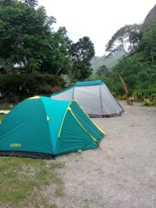 two tents in a field with trees in the background at Tapian Ratu Camp in Bukittinggi