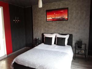 L'amarante chambres d'hôtes villefranche de panat في Villefranche-de-Panat: غرفة نوم بسرير ابيض ولوحة على الحائط