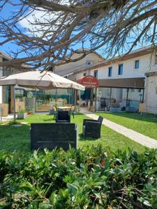 a park with two chairs and an umbrella at Hôtel La Parenthèse in Attignat