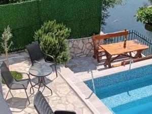 eine Terrasse mit einem Tisch und Stühlen neben einem Pool in der Unterkunft Vinarija "Đelmo" apartments in Trebinje