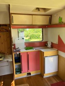 eine kleine Küche in einem Wohnwagen mit Fenster in der Unterkunft Unique 70s caravan, calm and relaxed in Les Cresnays