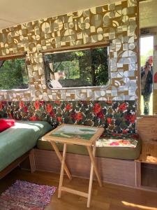 einem Tisch auf der Rückseite eines Anhängers mit einem Bett und einem Fenster in der Unterkunft Unique 70s caravan, calm and relaxed in Les Cresnays