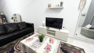 sala de estar con sofá negro y TV en Homestay Near Plaza Tol Bandar Ainsdale, en Labu