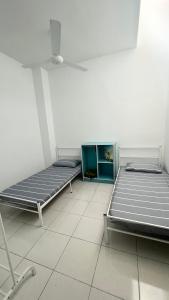 two beds are sitting in a room with a tiled floor at Homestay Near Plaza Tol Bandar Ainsdale in Labu