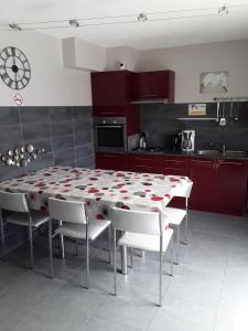 L'amarante chambres d'hôtes villefranche de panat في Villefranche-de-Panat: مطبخ مع طاولة وكراسي ودواليب حمراء