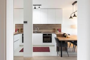 a kitchen with white cabinets and a wooden table at Stylish 2BDR Apartment- Free Garage in Zagreb
