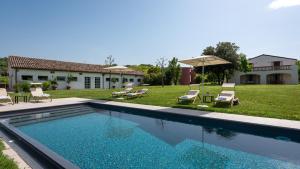 una piscina en un patio con sillas y sombrilla en LA CASA NEI VIGNETI 10, Emma Villas, en Catignano