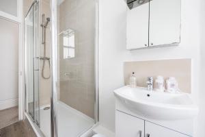a white bathroom with a sink and a shower at Leicester Square Apartment in London