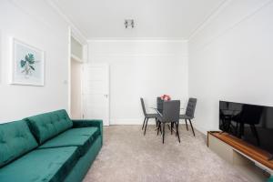 a living room with a green couch and a table at Leicester Square Apartment in London