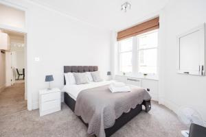 a white bedroom with a large bed and a window at Leicester Square Apartment in London