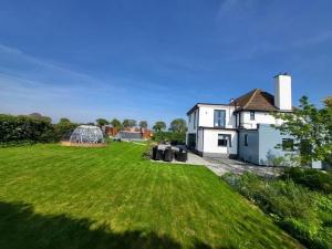 a large yard with a white house and a greenhouse at Covehithe House-Coastal luxury- sleeps 12-with huge swimspa! in Wrentham