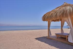 a straw umbrella and a bench on a beach at The Bayview Taba Heights Resort in Taba