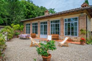 un patio con sedie e tavolo di fronte a una casa di La Serra Vitignano-Stunning Villa W/Swimming Pool! a Castelnuovo Berardenga