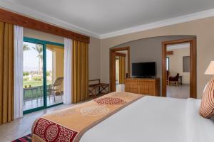 a bedroom with a bed and a balcony with a television at The Bayview Taba Heights Resort in Taba