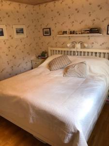 a white bed in a bedroom with floral wallpaper at Havsnära villa, närhet till stan in Värmdö