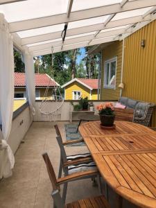 un patio con mesa de madera y sillas en Havsnära villa, närhet till stan, en Värmdö