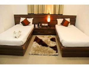 a room with two beds and a rug at Hotel Flora Inn, Nagpur in Nagpur