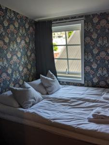 uma cama com almofadas e uma janela num quarto em Ulvö Hamnkrog em Ulvöhamn