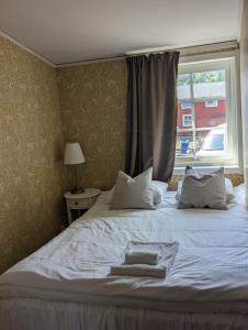 1 dormitorio con 1 cama con 2 almohadas y ventana en Ulvö Hamnkrog, en Ulvöhamn
