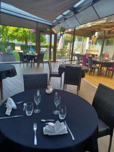 a black table with glasses and napkins on a patio at Hôtel La Parenthèse in Attignat