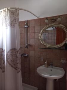 a bathroom with a shower curtain and a sink at Poly's Sea Side House in Koropi