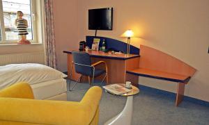 リューネンにあるRetro - Art - Hotel Lünenのデスク、ベッド、椅子が備わるホテルルームです。